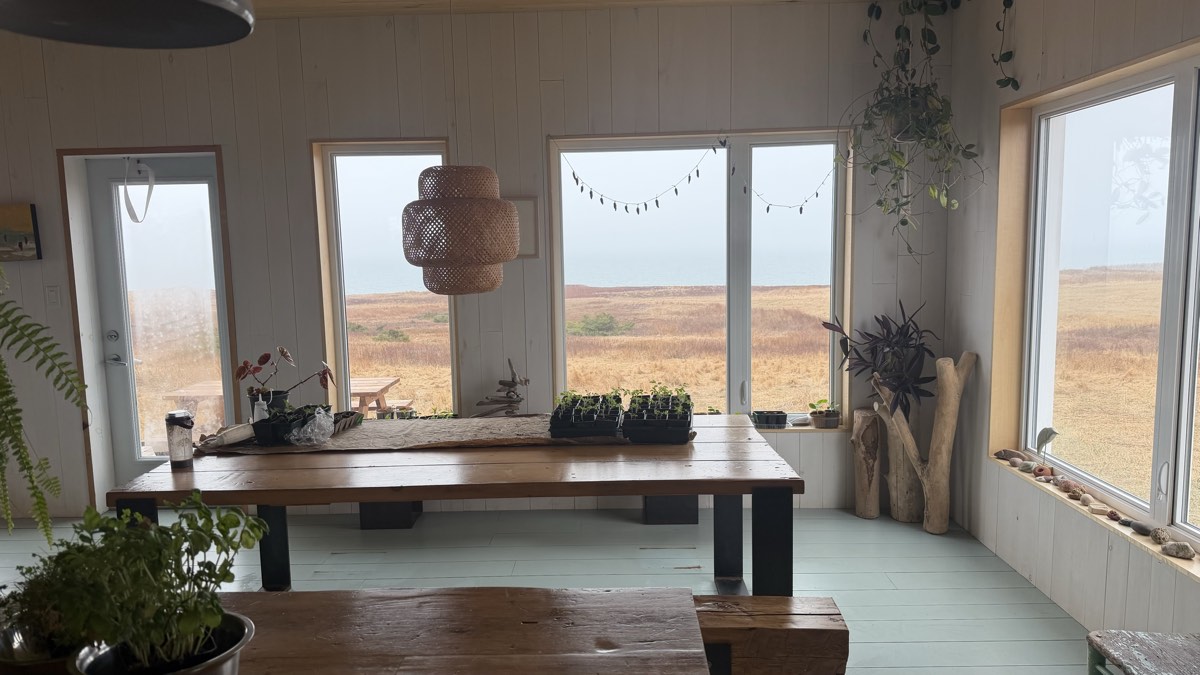 Salle à manger avec grande table de bois, fenêtres sur le paysage