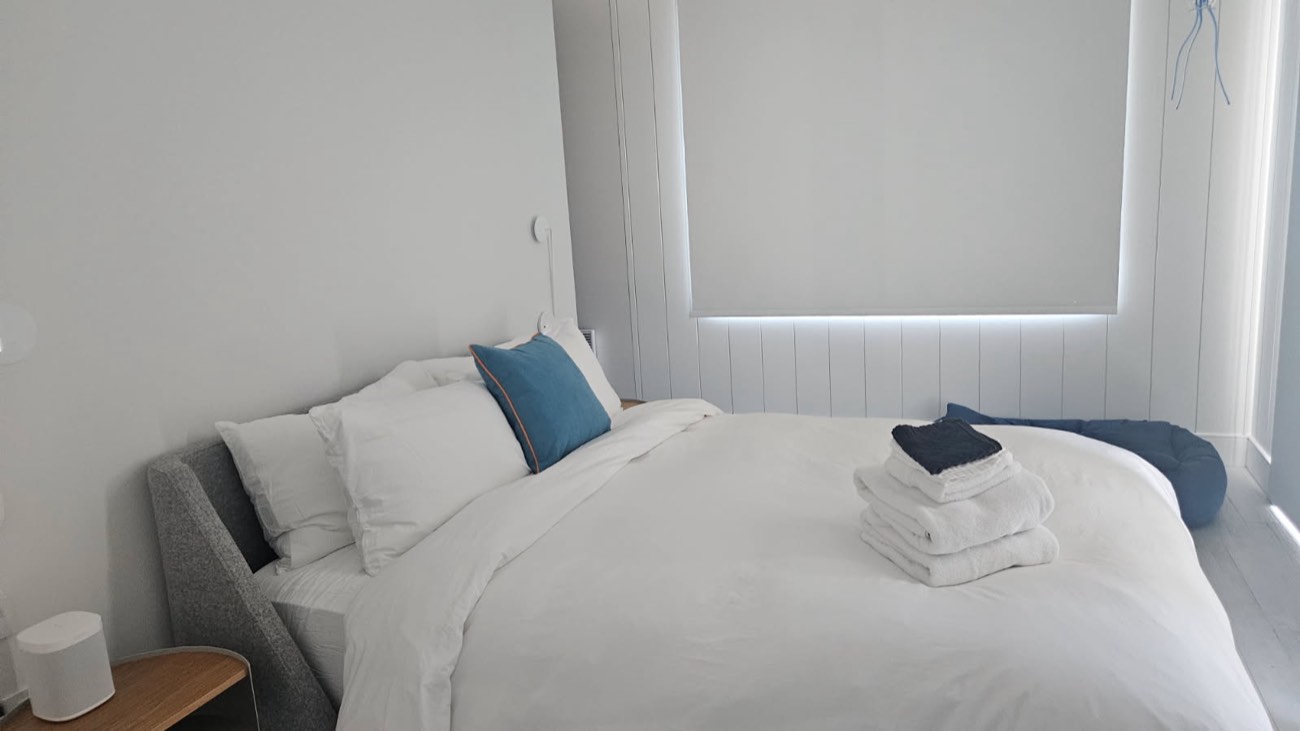 Chambre au grand lit fait, serviettes pliées sur la couette