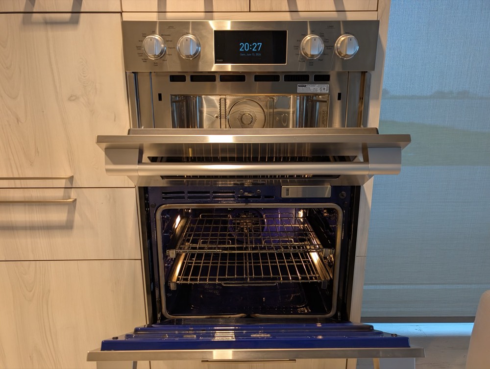 Four ouvert, grilles et intérieur propres, sous une plaque de cuisson