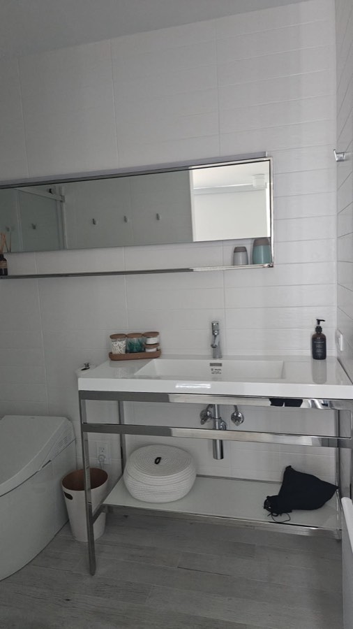 Lavabo, miroir et accessoires bien rangés dans une salle de bain blanche
